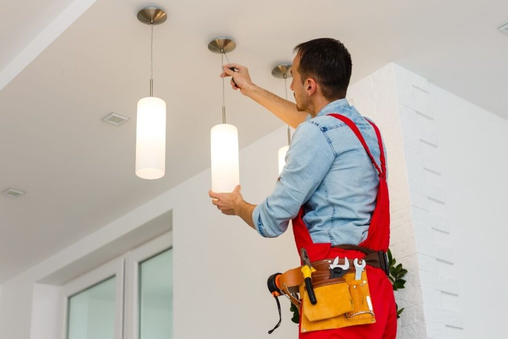 An electrician in Kansas City installs a lamp in a kitchen.